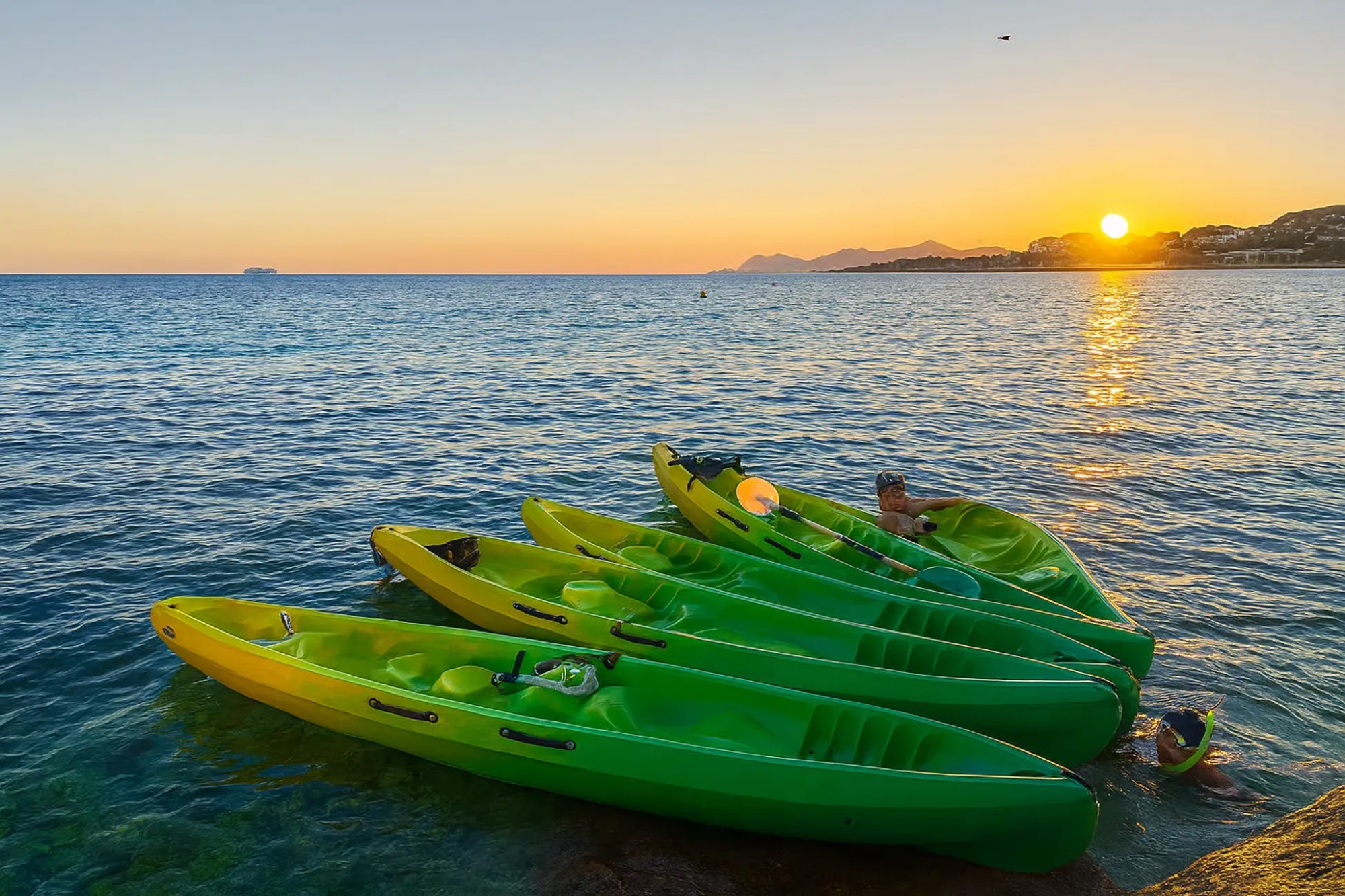 Kayaks verts au bord de l'eau au coucher du soleil